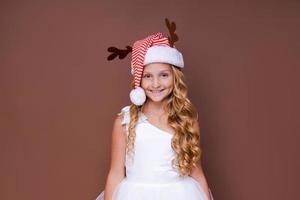Lycklig rolig barn flicka i röd jul rådjur kostym leende ser på kamera. foto