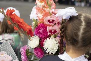 barn på dag av kunskap. förstaklassare gå till skola. barn med blommor för lärare. foto