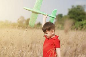 pojke Lycklig spelar med leksak plan i natur och klar morgon- himmel, barn begrepp och dröm plan till bli pilot. vilja till flyga tycka om ett flygplan foto