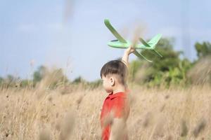 pojke Lycklig spelar med leksak plan i natur och klar morgon- himmel, barn begrepp och dröm plan till bli pilot. vilja till flyga tycka om ett flygplan foto
