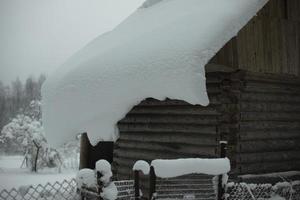 hus i by i vinter. massor av snö på tak av gammal hus. foto