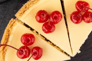 klassisk cheesecake dekorerad med körsbär på en mörk bakgrund foto