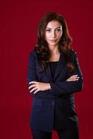 skön ung företag kvinna i en kostym på en röd bakgrund foto