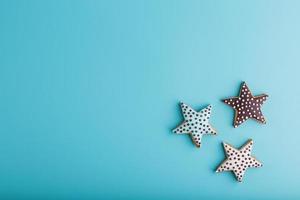 närbild av tre hemlagad glaserad pepparkaka småkakor tillverkad i de form av stjärnor på en blå bakgrund. handgjort småkakor. fri Plats. foto