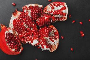 de öppnad frukt av en mogen öppen granatäpple lögn på en svart textural bakgrund. foto