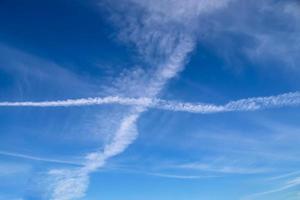 flygplanskondensation drar ihop sig på den blå himlen mellan några moln foto