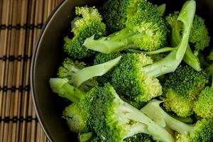massa färsk grön broccoli i skål över träbakgrund foto
