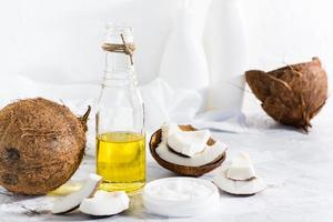 två typer av kokos olja i en burk och en flaska och bitar av kokos på de tabell. naturlig kosmetika. foto