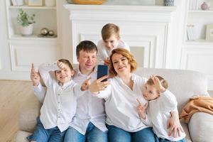 Lycklig kärleksfull familj fem använder sig av smartphone för video kallelse med familj foto