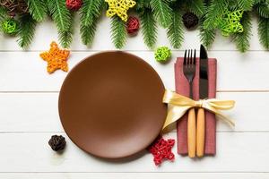 topp se av ny år middag på festlig trä- bakgrund. sammansättning av tallrik, gaffel, kniv, gran träd och dekorationer. glad jul begrepp foto