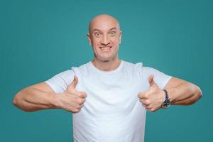 ett emotionell man i en vit t-shirt visar med en hand gest den där allt är Häftigt, på en titian bakgrund foto