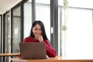 Lycklig ung asiatisk Söt kvinna video ring upp chatt på digital bärbar dator dator på kaffe. foto