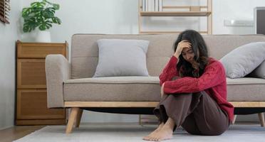 deprimerad ensam olycklig mental kvinna Sammanträde ensam på de soffa på Hem med hand på ansikte känna påfrestning ledsen och orolig besvikelse medan vänd problem under coronavirus eller covid-19 pandemi foto