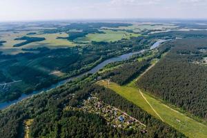 antenn panorama- se av grön by med hus i skog nära bred flod foto