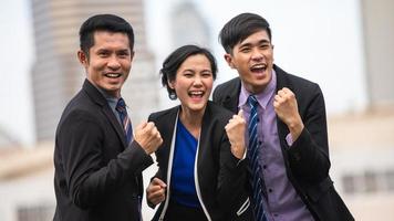 asiatisk företag män och kvinnor uttrycka glädje och lycka i de framgångsrik arbete utanför kontor foto