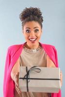 skön attraktiv glad leende ung blandad ras kvinna innehav gåva låda i henne händer. jul, svart fredag, handla, vänskap begrepp foto