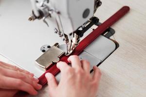 en läder hantverkare producerar läder varor på en sömnad maskin i hans affär. foto