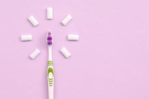tandborste och tugga tandkött lögn på en pastell rosa bakgrund foto
