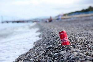 antalya, Kalkon - Maj 18, 2021 original- coca cola röd tenn kan lögner på små runda sten stenar stänga till hav Strand. Coca Cola på turkiska strand foto