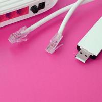 internet router, bärbar uSB Wi-Fi adapter och internet kabel- pluggar lögn på en ljus rosa bakgrund. objekt nödvändig för internet foto