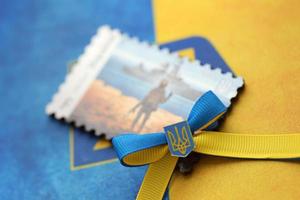 ternopil, ukraina - september 2, 2022 känd ukrainska poststämpel med ryska örlogsfartyg och ukrainska soldat som trä- souvenir på nationell flagga foto
