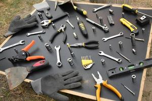 hantlangare verktyg utrustning på svart trä- tabell. många Nycklar och skruvmejslar, pålar och Övrig verktyg för några typer av reparera eller konstruktion Arbetar. reparatör verktyg foto