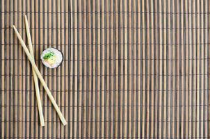 sushi rulla och trä- ätpinnar lögn på en bambu sugrör serving matta. traditionell asiatisk mat. topp se. platt lägga minimalism skott med kopia Plats foto