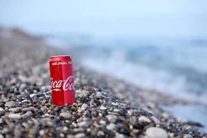 antalya, Kalkon - Maj 18, 2021 original- coca cola röd tenn kan lögner på små runda sten stenar stänga till hav Strand. Coca Cola på turkiska strand foto