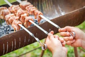 händer av man förbereder utegrill kött foto