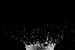 vatten stänk och droppar isolerat på svart bakgrund. foto