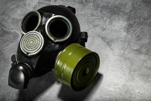 gas mask på en svart sten bakgrund med en grön filtrera patron. postapokalyptisk begrepp. foto