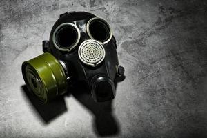 gas mask på en svart sten bakgrund med en grön filtrera patron. postapokalyptisk begrepp. foto