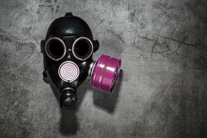 gas mask på en svart sten bakgrund med en rosa filtrera patron. postapokalyptisk begrepp. foto