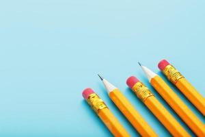 orange pennor med ett suddgummi på en blå bakgrund. foto
