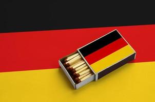 Tyskland flagga är visad i ett öppen tändsticksask, som är fylld med tändstickor och lögner på en stor flagga foto