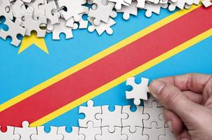 demokratisk republik av de kongo flagga är avbildad på en tabell på som de mänsklig hand veck en pussel av vit Färg foto
