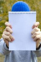 tonåring pojke innehav en anteckningsbok i hans händer utomhus. selektiv fokus foto