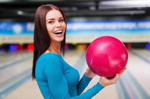 min tur- boll. skön ung kvinnor innehav en bowling boll medan stående mot bowling gränder foto