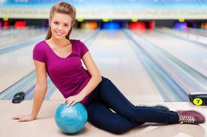 skönhet på de bowling gränd.vacker ung kvinnor Sammanträde på de golv mot bowling gränder foto