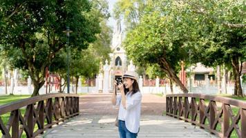 ung asiatisk kvinna resande tar bilder på bidge , tempel bakgrund foto
