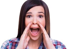 delning färsk Nyheter med du. överraskad ung kvinna skrikande medan innehav händer runt om mun medan isolerat på vit foto