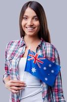 skönhet med australier flagga. Lycklig ung kvinnor flagga av Australien medan stående mot grå bakgrund foto