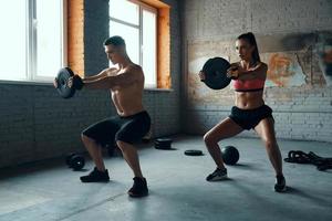 ung passa par ser koncentrerad medan håller på med vikt Träning i Gym tillsammans foto