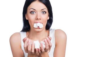 marshmallow paradis. skön kvinnor innehav marshmallow i henne mun och händer medan stående mot vit bakgrund foto