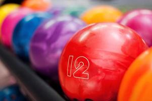 mängd av färger. närbild av ljus röd bowling boll liggande i de rader av Övrig färgrik bollar foto