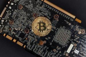 kryptovaluta gyllene bitcoin mynt liggande på video kort. elektronisk virtuell pengar för webb bank och internationell nätverk betalning. symbol av crypto virtuell valuta. brytning begrepp. foto