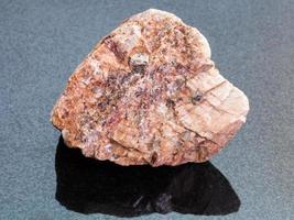 grov rosa granit sten på mörk bakgrund foto