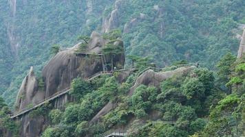 de skön bergen landskap med de grön skog och en planka väg byggd längs de ansikte av en klippa i de landsbygden av de Kina foto