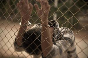 närbild Foto av händer i fängelse stål maska hantera handtag de stål maska bur, saknar oberoende.