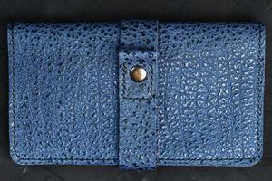 blå läder plånbok på en svart texturerad bakgrund. foto